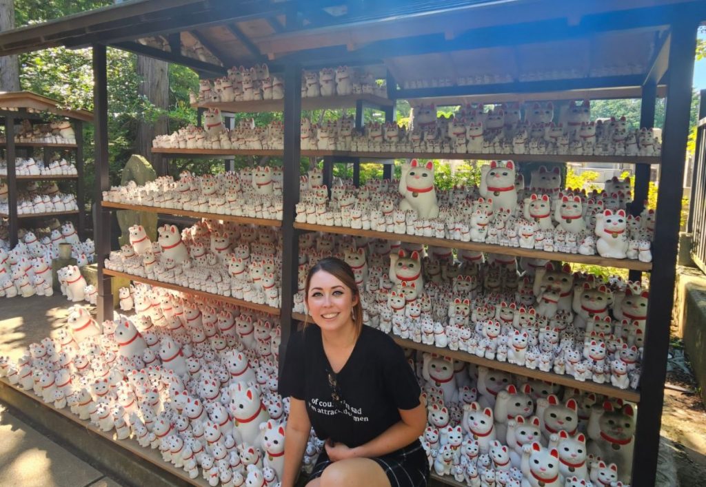 Me sitting in front of the large collection of white cat figurines at Gotoku-ji Cat temple in Tokyo, Japan (Gotokuji)