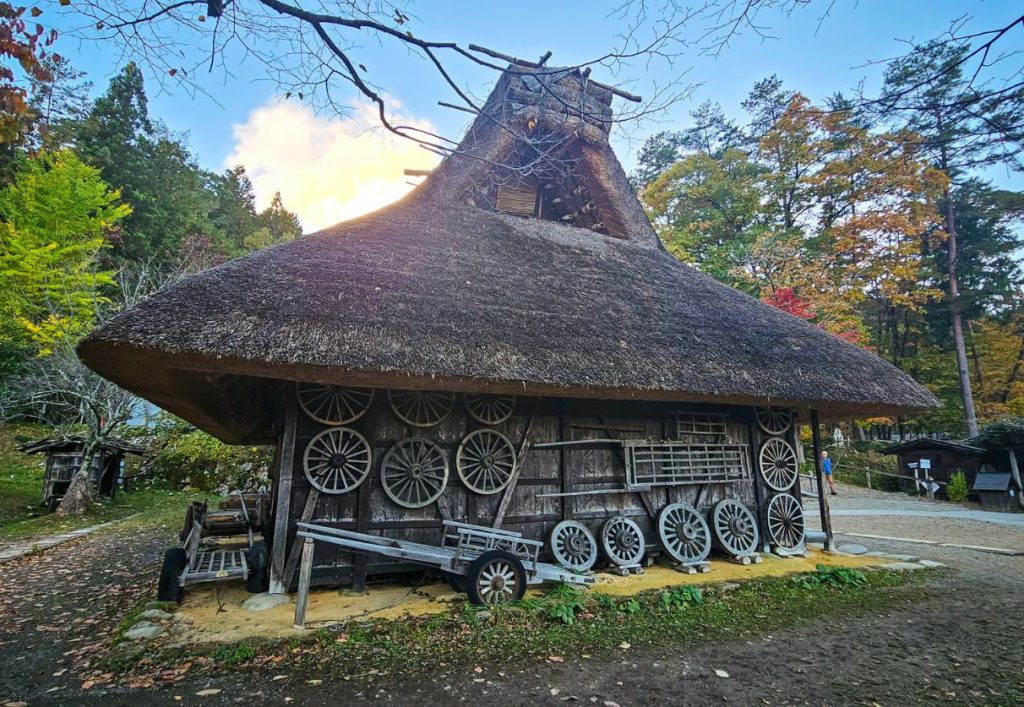 One of the traditional houses with old-fashioned wooden wheels and farm equipment Hida no Sato