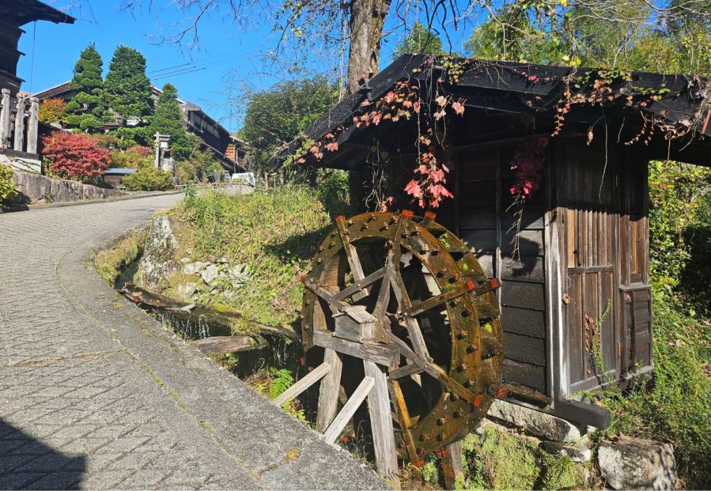 A small water wheel next to a persons home in the village